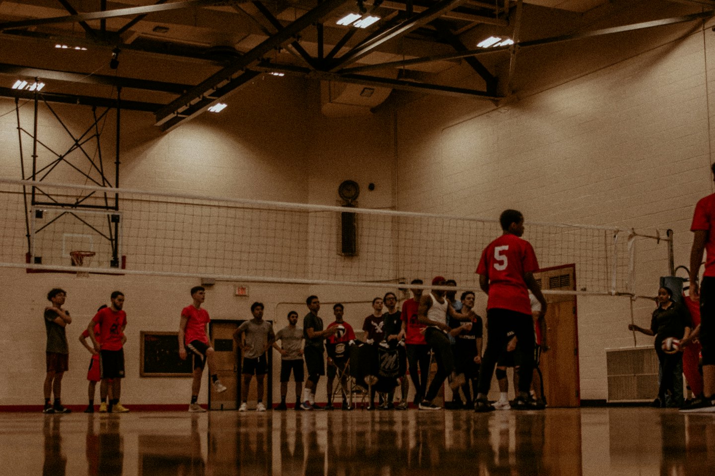 Unga vuxna spelar volleyboll i en gymsal.